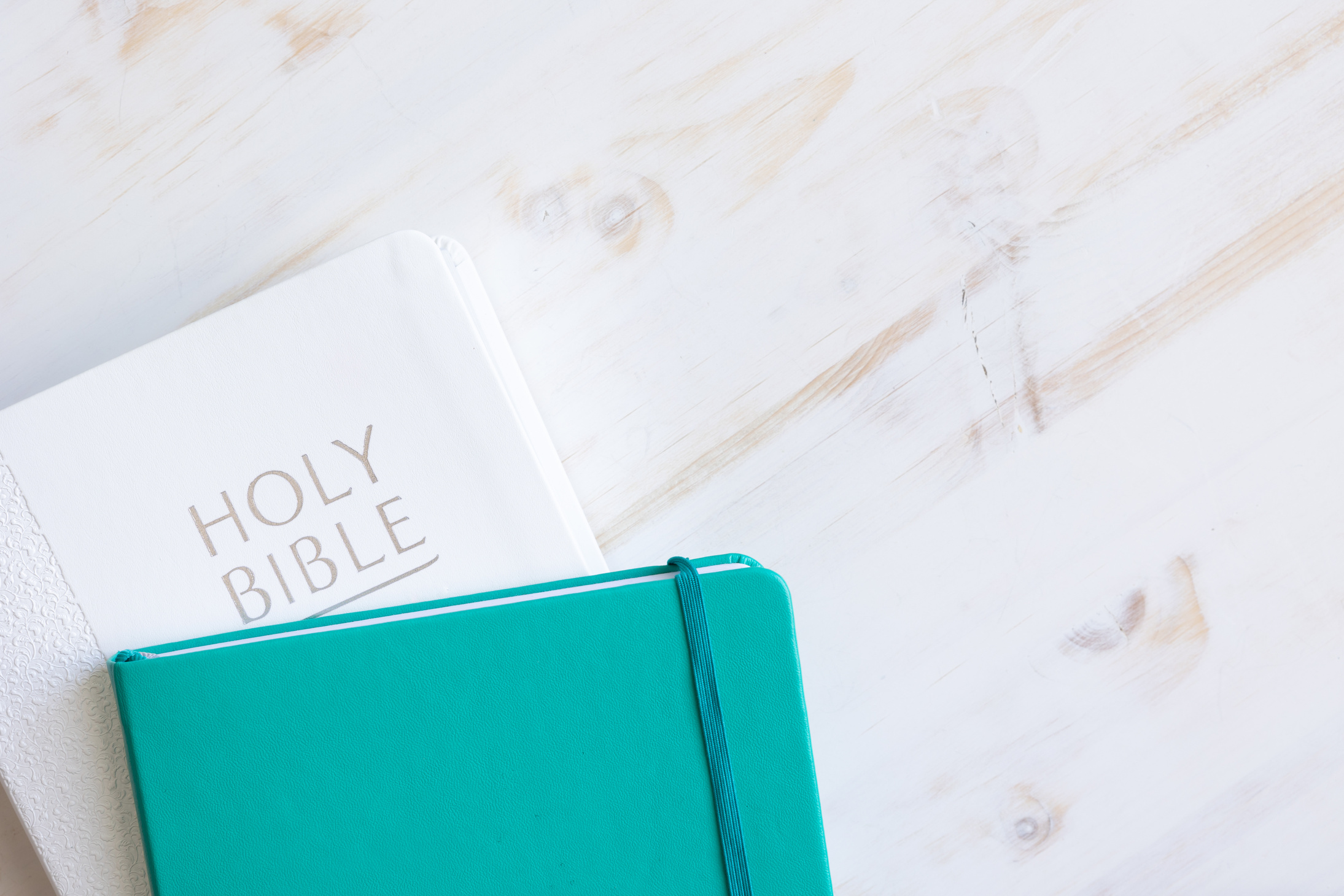 White bible and teal journal on white
